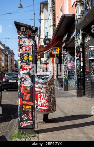 Autocollant sur le distributeur de billets de stationnement, poubelle et entrée de la maison sur la rue Zuelpicher, Cologne, Allemagne. Aufkleber auf Parkscheinautomat, Abfalleimer u Banque D'Images
