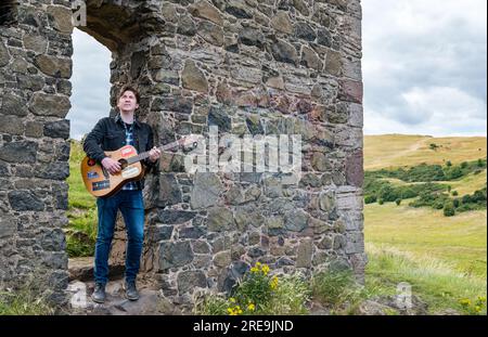 Mike Baillie, musicien The Lonely Together, joue de la guitare aux ruines de la chapelle St Anthony, Holyrood Park, Édimbourg, Cotland, Royaume-Uni Banque D'Images