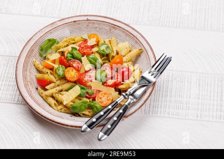 Une délicieuse assiette de pâtes italiennes ornée de tomates fraîches et de feuilles de basilic aromatiques. Avec espace de copie Banque D'Images