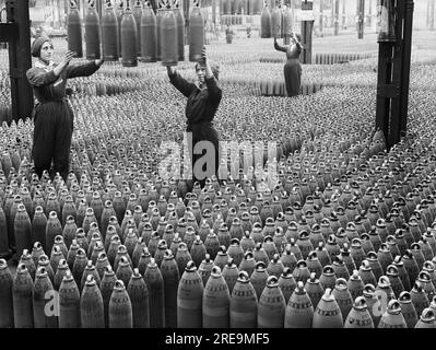 Horace Nicholls - des ouvrières de munitions de sexe féminin guident des obus obusiers de 6 pouces qui sont abaissés au sol à l'usine nationale de remplissage de coquillages à Chilwell. Banque D'Images