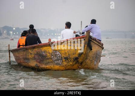 Des gens dans un bateau sur le gange à Veranassi. Les gens préparent des bûchers funéraires à Varanasi sur les rives du Gange, qui est l'une des plus anciennes villes continuellement habitées dans le monde, et la plus sainte des sept villes sacrées de l'hindouisme. Chaque jour, à Manikarnika Ghat, le ghat de crémation le plus grand et le plus propice, environ 100 corps sont incinérés sur des bûchers en bois le long du bord de la rivière. On dit que la flamme éternelle qui alimente les feux brûle depuis des siècles maintenant. Varanasi, Inde. Banque D'Images