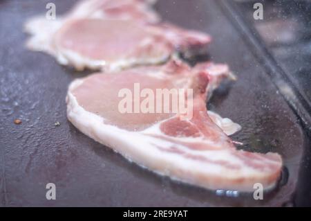 Steak de porc sur un barbecue maison qui est sur le dessus d'un poêle, concept de faire de la nourriture à la maison. Banque D'Images