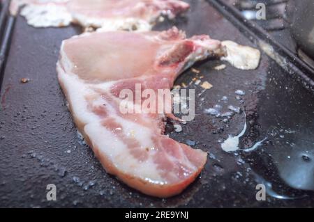 Steak de porc sur un barbecue maison qui est sur le dessus d'un poêle, concept de faire de la nourriture à la maison. Banque D'Images