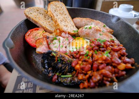 Petit déjeuner anglais complet avec bacon, saucisse, œuf au plat, haricots et champignons. nourriture servie dans une casserole. mise au point sélective. Banque D'Images