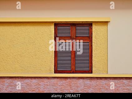 Simple fenêtre en bois dans un mur jaune chaud d'une maison de villa. Banque D'Images