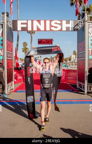 Huntington Beach, Californie, États-Unis. 21 avril 2018. Le vainqueur d'une épreuve de triathlon sur piste à Huntington Beach, CA, agite triomphalement le ruban de la ligne d'arrivée. (Image de crédit : © Spencer Grant/ZUMA Press Wire) USAGE ÉDITORIAL SEULEMENT! Non destiné à UN USAGE commercial ! Banque D'Images