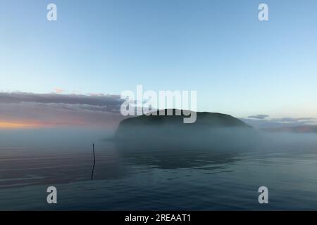 Petite île de Lille Kamøya tard un soir d'août juste à l'extérieur du village de pêcheurs de Kamøyvær avec soleil de minuit et brouillard de mer. Banque D'Images