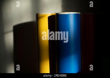 Papier bleu et jaune. Film bleu et jaune en rouleaux. Film auto-adhésif sur fond de mur. Matériel créatif. Banque D'Images