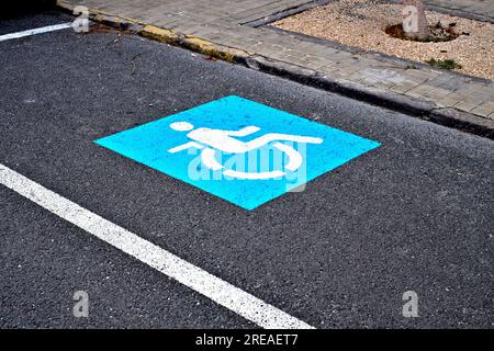 Symbole bleu de fauteuil roulant marquant une place de stationnement réservée aux conducteurs ayant un handicap physique. Banque D'Images