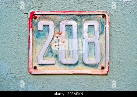 Numéro 208, deux cent huit, une assiette vintage sur un mur bleu. Banque D'Images