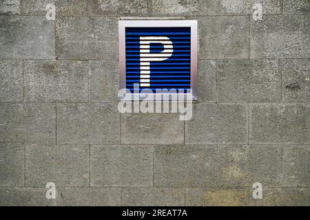 Grand panneau de stationnement bleu sur un mur de pierre. Banque D'Images