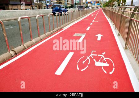 Pistes cyclables rouge vif clairement marquées avec le symbole de vélo dans le pochoir. Banque D'Images