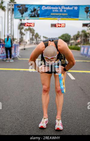 Huntington Beach, Californie, États-Unis. 14 octobre 2018. Épuisé après avoir franchi la ligne d'arrivée, un coureur de compétition de 10 miles se penche pour reprendre son souffle alors qu'il tient un ruban signifiant qu'il termine la course à Huntington Beach, en Californie. (Image de crédit : © Spencer Grant/ZUMA Press Wire) USAGE ÉDITORIAL SEULEMENT! Non destiné à UN USAGE commercial ! Banque D'Images