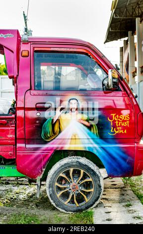 Oslob, Cebu, Philippines-janvier 27 2023 : garé à côté de l'église Oslob, un petit camion-camionnette improvisé, est décoré avec flamboyant et un peu humo Banque D'Images