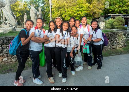 Oslob, Cebu, Philippines-janvier 27 2023 : les passants près de l'église catholique Immaculée conception, les adolescents philippins locaux, demandent avec enthousiasme Banque D'Images