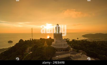 Vue aérienne Phuket grand Bouddha dans le magnifique coucher de soleil. Soleil étonnant brille à travers les nuages jaunes impact sur la surface dorée de la mer la beauté de la statue Banque D'Images