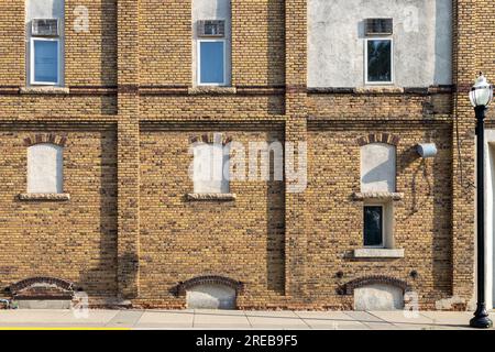 Fond de texture d'une vieille façade de bâtiment en briques jaunes et brunes avec vue sur les fenêtres cintrées fermées sur une rue urbaine Banque D'Images