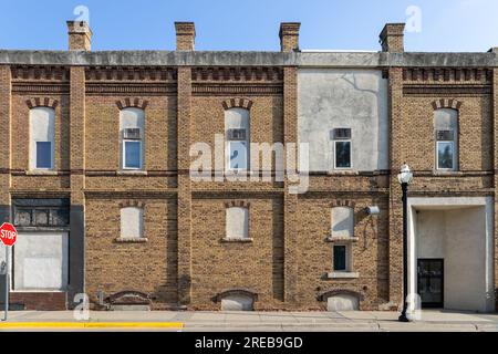 Fond de texture d'une vieille façade de bâtiment en briques jaunes et brunes avec vue sur les fenêtres cintrées fermées sur une rue urbaine Banque D'Images