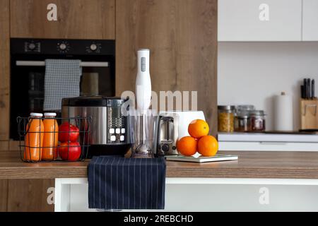 Multi cuisinière, mixeur, grille-pain et balance avec des oranges sur la table en bois dans la cuisine Banque D'Images