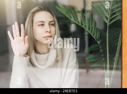 Fille triste près de la fenêtre pensant à quelque chose. Une dame stressée se sent seule Banque D'Images