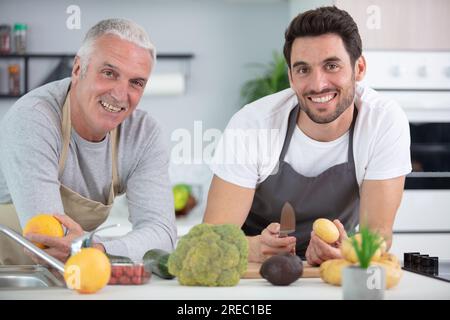 deux hommes préparant des légumes pour le repas à la maison Banque D'Images