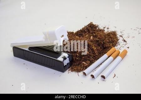 sur un fond blanc tabac et un outil pour la fabrication de cigarettes, contrebande de cigarettes Banque D'Images