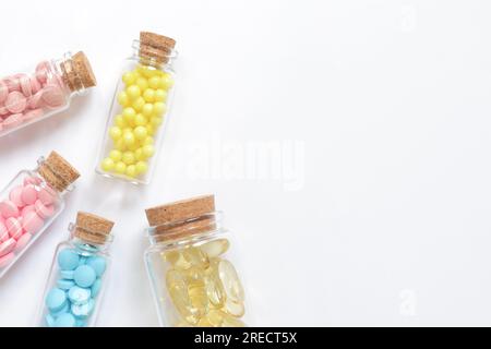 Vitamines de différentes couleurs dans des bouteilles en verre sur fond blanc, vue de dessus. Placer pour le texte, copier l'espace. Vitamines, analgésiques, soins de santé, santé p Banque D'Images