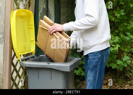 Une personne qui trie les déchets d'emballage. Homme mettant des boîtes d'emballage dans le bac jaune pour le recyclage Banque D'Images