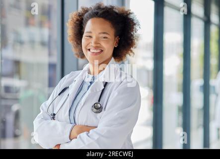 Femme noire heureuse, portrait et médecin avec les bras croisés en clinique pour des services de bien-être, de l'aide ou des consultations médicales. Médecine, santé et jeunesse Banque D'Images