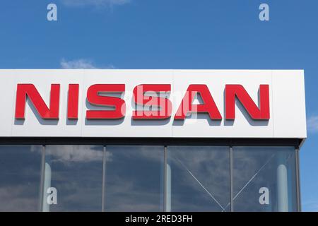 Pologne, Przezmierowo - 27 juillet 2023 : le logo de la marque Nissan, appartenant au plus grand constructeur de véhicules électriques au monde, se dresse contre un ciel bleu ba Banque D'Images