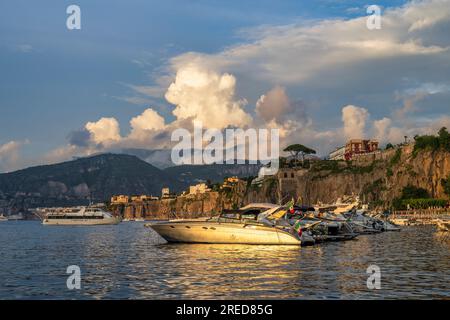 Bateaux amarrés à Marina Piccola baignés de lumière dorée alors que le soleil se couche à travers la baie de Naples à Sorrente dans la région Campanie du sud-ouest de l'Italie Banque D'Images