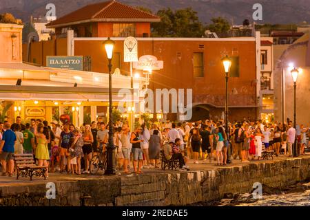 CRÈTE, GRÈCE - JUILLET 03 2023 : des foules de touristes se rassemblent dans les restaurants dans la soirée autour du vieux port vénitien de Chania, dans l'ouest de la Crète Banque D'Images