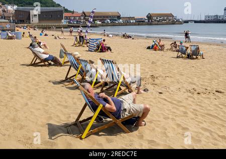 Personnes touristes visiteurs se détendant sur des transats South Bay Beach en été Scarborough North Yorkshire Angleterre Royaume-Uni GB Grande-Bretagne Banque D'Images