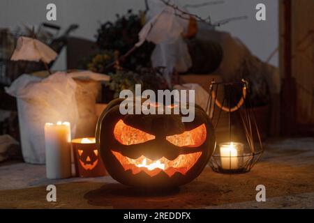 Spooky Jack o lanterne, araignées, citrouille et bougies brillantes dans l'obscurité. Porche d'Halloween et décoration d'entrée. Décorations effrayantes d'halloween à l'extérieur de la maison. Banque D'Images