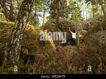 Un grimpeur au loin à l'escalade rochers rochers et arbres dans la forêt d'escalade et de blocs de Fontainebleau près de Paris en France Banque D'Images