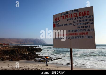 Plage dangereuse, baignade interdite signe avec numéros de téléphone d'urgence à Playa Brava sur la côte Pacifique juste au sud d'Arica, Chili Banque D'Images