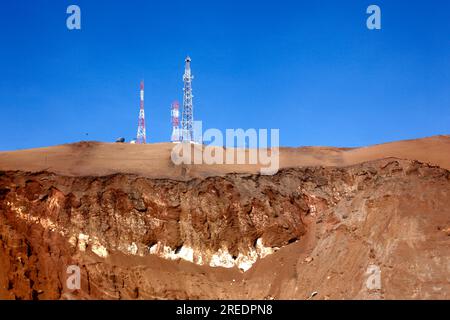 Téléphones mobiles / radios mâts et strates de roche sur la colline du désert de Cerro El Morro Gordo près du promontoire d'El Morro, près d'Arica, Chili Banque D'Images