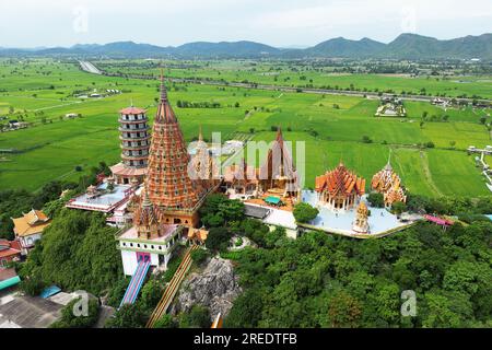 Wat Tham Sua sur la colline supérieure avec des champs de riz vert ciel bleu dans la province de Kanchanaburi Thaïlande. Banque D'Images