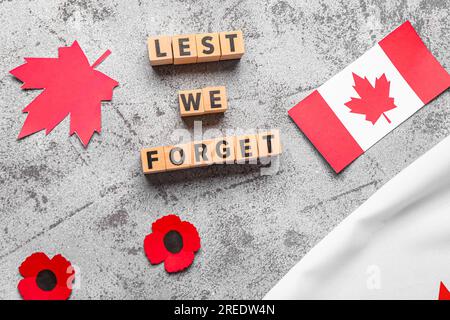 Fleurs de coquelicot avec drapeaux du Canada et texte DE PEUR QUE NOUS OUBLIIONS sur fond gris grunge. Jour du souvenir Banque D'Images