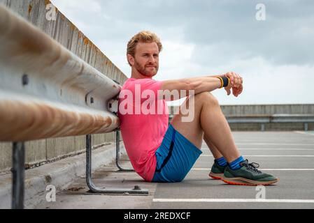 FIT sportif homme se reposant après l'exercice de course, fond urbain Banque D'Images