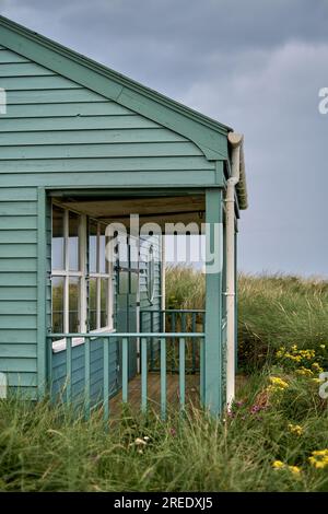 Une maison de plage en bois vert dans les dunes de sable dans le Northumberland Banque D'Images