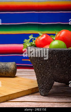 Molcajete avec des légumes sur une table en bois. Ingrédients pour une sauce piquante. Banque D'Images