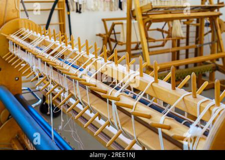 Gros plan de chevilles de gauchissement sectionnelles d'un métier à tisser dans un atelier de tissage de textiles Banque D'Images