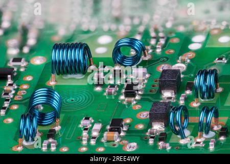 Inductances à noyau d'air bleu à partir d'un fil métallique sur une carte de circuit imprimé verte du module RF de carte TV. Bobine spirale plane en gros plan et composants électroniques. PCB Banque D'Images