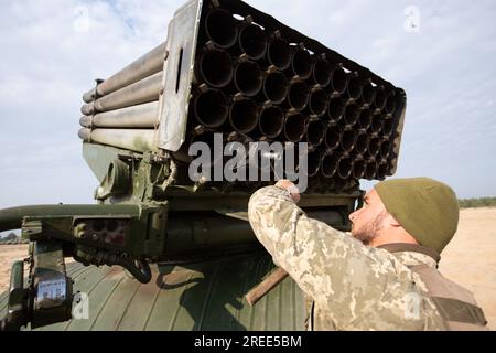 Soldat de l'armée ukrainienne charge un système de lance-roquettes multiples BM-21 Grad pendant des exercices au champ d'artillerie près du village de Divychky, région de Kiev. Banque D'Images