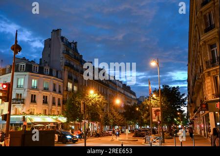 Paris, France, juin 2022. Vue d'un carrefour du centre-ville la nuit. Les bâtiments de style typiquement parisien encadrent la rue éclairée par la rue lam Banque D'Images