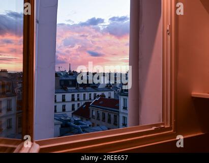 Paris France juin 2022. Vue depuis la fenêtre d'un coucher de soleil envoûtant sur la ville. Reconnaissable la tour Eiffel qui se démarque parmi les toits de t Banque D'Images