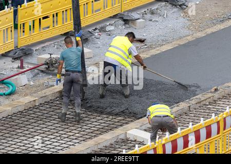 Galice, Espagne ; 20 juillet 2023 : travailleurs travaillant sur une route urbaine qui coule du béton sur un chantier de construction Banque D'Images