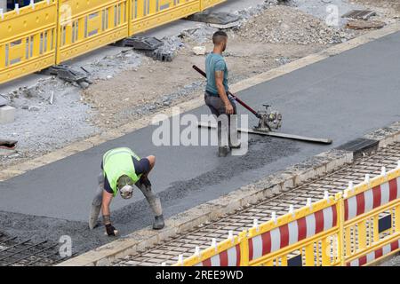 Galice, Espagne ; 20 juillet 2023 : ouvriers travaillant sur une route de ville à polir le béton sur un chantier de construction Banque D'Images