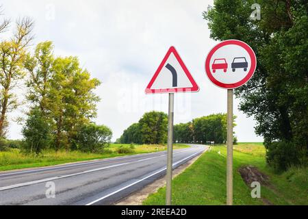 Panneaux de signalisation, dépassement est interdit et un virage dangereux sur le fond de la piste Banque D'Images